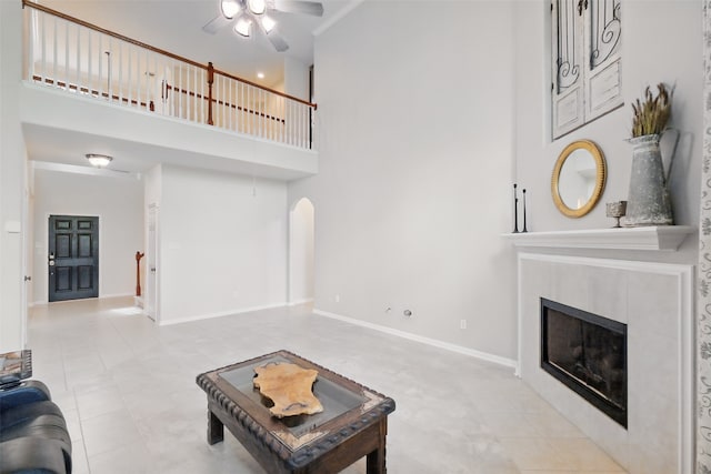 9034 Cedar Run Fls, Tomball, TX 77375 - living area with a high ceiling, ceiling fan, arched walkways, a tiled fireplace, and baseboards