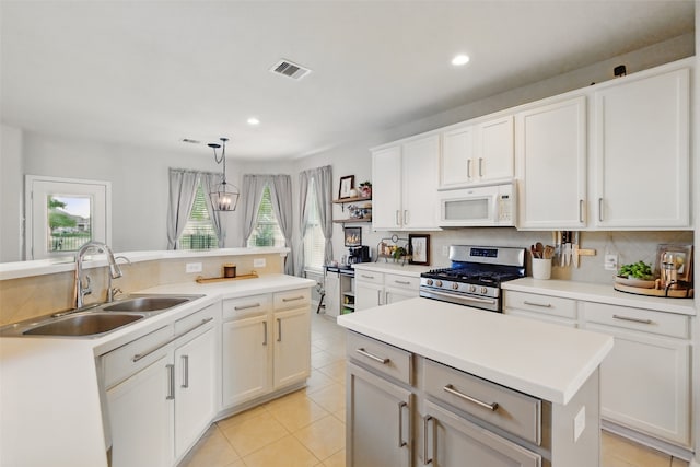 9034 Cedar Run Fls, Tomball, TX 77375 - kitchen featuring stainless steel gas range oven, white microwave, a sink, a center island, and decorative backsplash