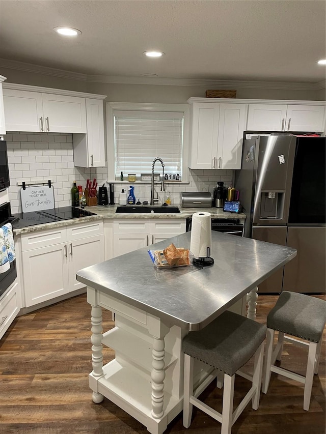 12955 Mintwood Dr, Beaumont, TX 77713 - kitchen featuring black appliances, a sink, stainless steel countertops, ornamental molding, and a breakfast bar area