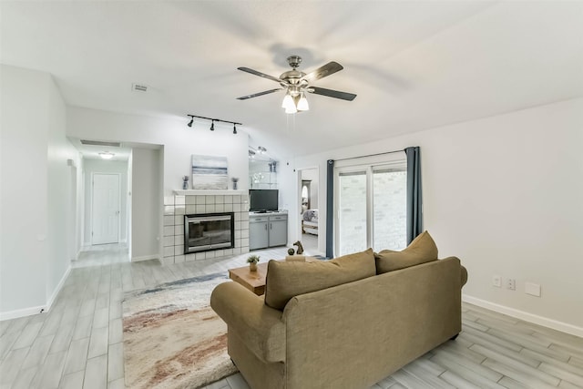 9819 Orangevale Dr, Spring, TX 77379 - living room featuring ceiling fan, light wood-style flooring, baseboards, a tiled fireplace, and lofted ceiling