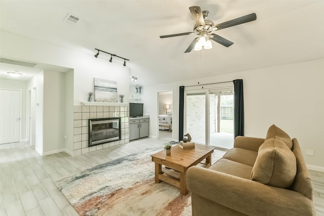 9819 Orangevale Dr, Spring, TX 77379 - living room featuring ceiling fan, a tiled fireplace, lofted ceiling, light wood-style flooring, and baseboards