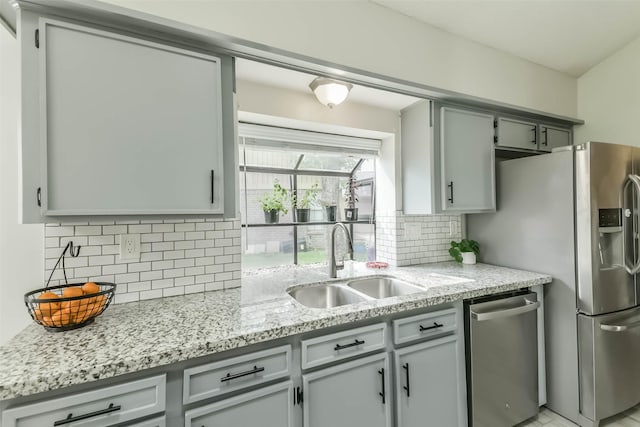 9819 Orangevale Dr, Spring, TX 77379 - kitchen with appliances with stainless steel finishes, a sink, decorative backsplash, light stone counters, and gray cabinetry