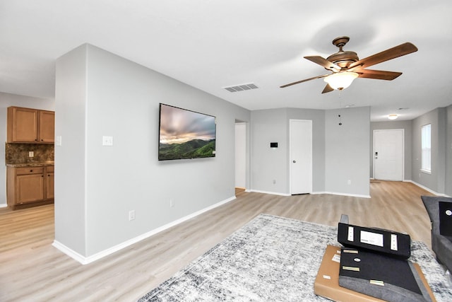 8907 Wildbird Ln, Humble, TX 77338 - unfurnished living room featuring light wood-style floors, ceiling fan, and baseboards