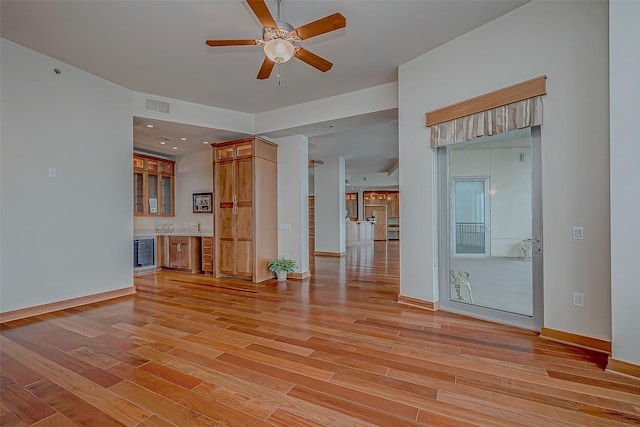 801 E Beach Dr Unit Tw2806, Galveston, TX 77550 - unfurnished living room featuring wet bar, ceiling fan, light wood-type flooring, and baseboards