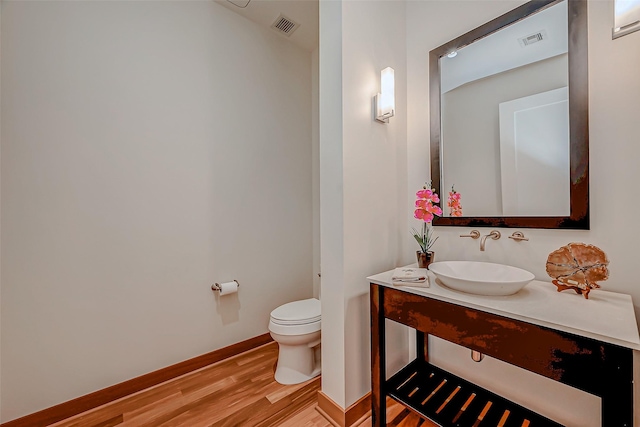 801 E Beach Dr Unit Tw2806, Galveston, TX 77550 - half bath featuring wood finished floors, toilet, baseboards, and vanity