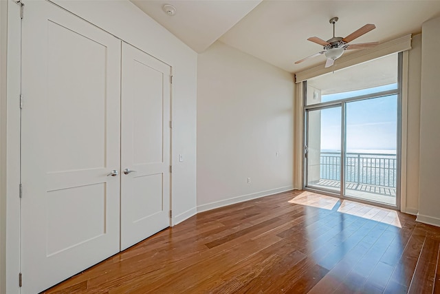 801 E Beach Dr Unit Tw2806, Galveston, TX 77550 - unfurnished bedroom featuring a wall of windows, access to exterior, hardwood / wood-style floors, baseboards, and ceiling fan