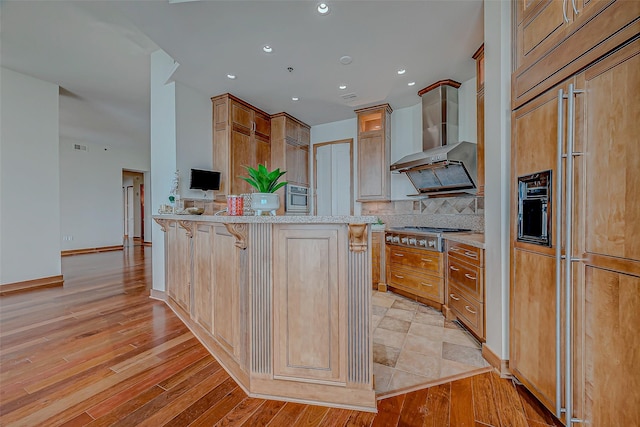 801 E Beach Dr Unit Tw2806, Galveston, TX 77550 - kitchen with stainless steel appliances, wall chimney range hood, backsplash, a peninsula, and light wood-style flooring