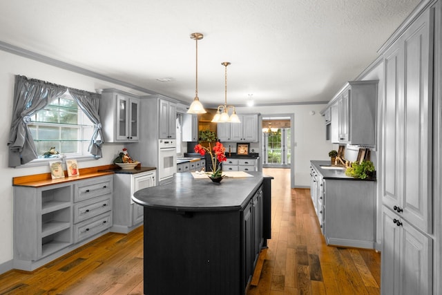 13106 Lookout Mountain Ct, Houston, TX 77069 - kitchen featuring dark countertops, oven, gray cabinetry, wood-type flooring, and crown molding