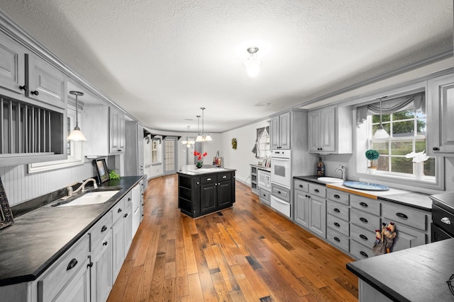 13106 Lookout Mountain Ct, Houston, TX 77069 - kitchen featuring gray cabinets, oven, dark countertops, light wood-style flooring, and a textured ceiling