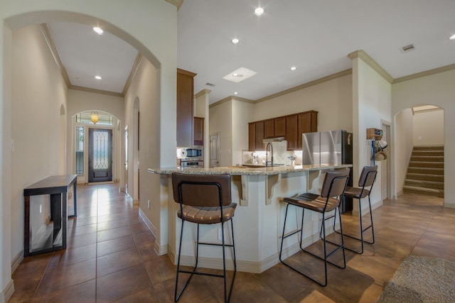 14610 Thunder Bay, Beach City, TX 77523 - kitchen with ornamental molding, brown cabinetry, a sink, appliances with stainless steel finishes, and light stone countertops