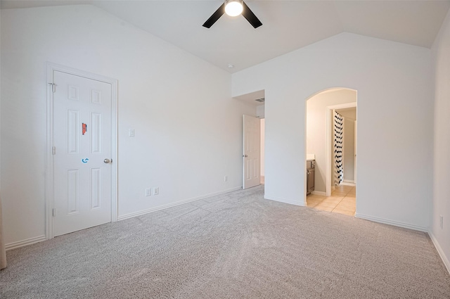 5003 Crystal Wind Ln, Katy, TX 77494 - spare room featuring vaulted ceiling, arched walkways, ceiling fan, light colored carpet, and baseboards