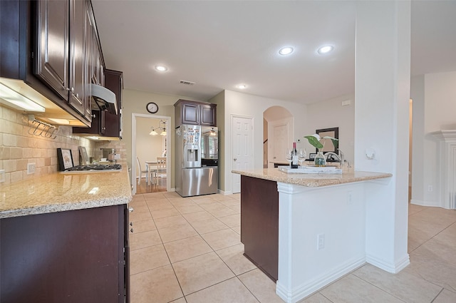 5003 Crystal Wind Ln, Katy, TX 77494 - kitchen featuring stainless steel appliances, light tile patterned floors, dark brown cabinetry, arched walkways, and recessed lighting