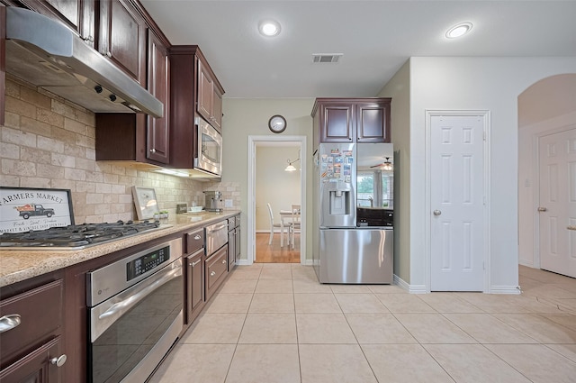5003 Crystal Wind Ln, Katy, TX 77494 - kitchen featuring stainless steel appliances, under cabinet range hood, light tile patterned floors, and backsplash