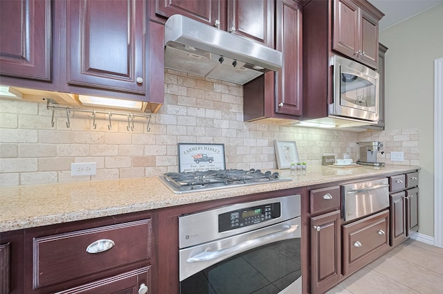 5003 Crystal Wind Ln, Katy, TX 77494 - kitchen featuring stainless steel appliances, under cabinet range hood, a warming drawer, backsplash, and light tile patterned floors