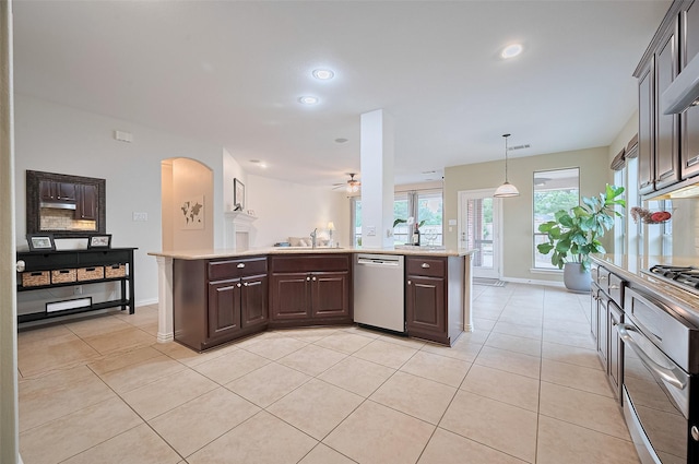 5003 Crystal Wind Ln, Katy, TX 77494 - kitchen featuring stainless steel appliances, arched walkways, dark brown cabinets, light tile patterned floors, and recessed lighting