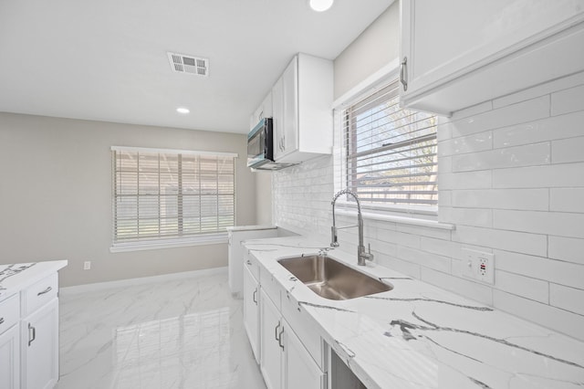 2414 Camillia St, Highlands, TX 77562 - kitchen with light stone countertops, white cabinets, a sink, light marble finish flooring, and decorative backsplash