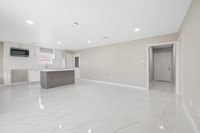 2414 Camillia St, Highlands, TX 77562 - unfurnished living room featuring light marble finish floors, baseboards, recessed lighting, and a sink