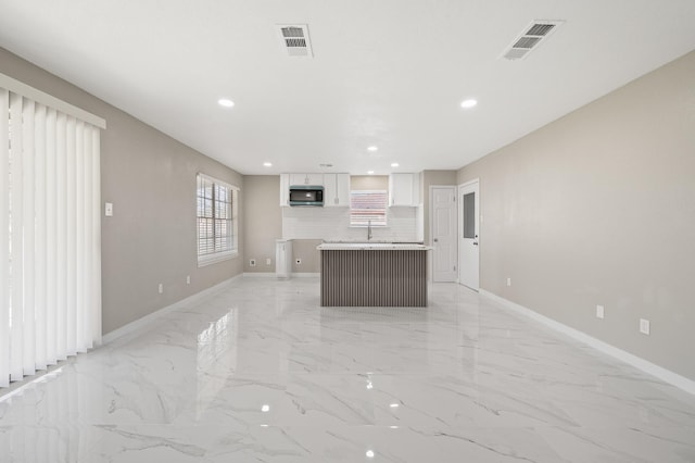 2414 Camillia St, Highlands, TX 77562 - kitchen with a center island, white cabinetry, light marble finish floors, recessed lighting, and baseboards