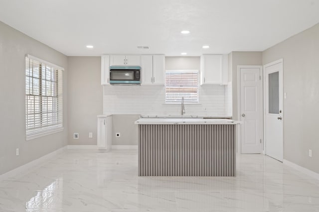 2414 Camillia St, Highlands, TX 77562 - kitchen with stainless steel microwave, light marble finish floors, decorative backsplash, white cabinets, and recessed lighting