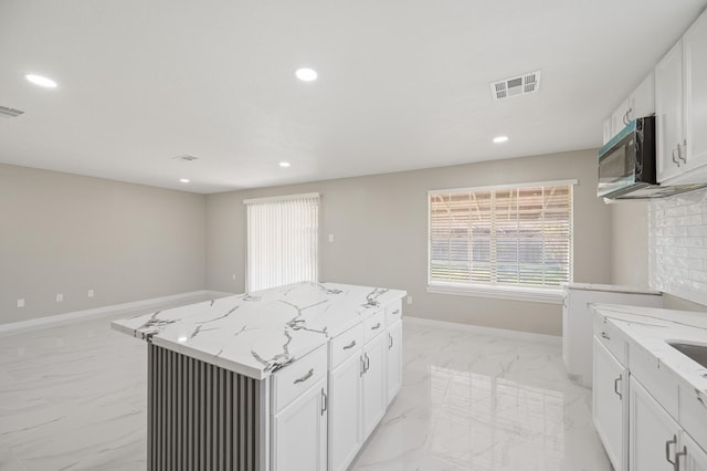 2414 Camillia St, Highlands, TX 77562 - kitchen with stainless steel microwave, light marble finish flooring, light stone countertops, recessed lighting, and baseboards