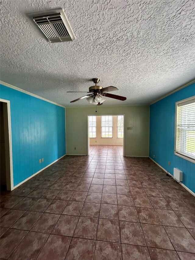 125 Mimosa Pt, Livingston, TX 77351 - tiled empty room with healthy amount of natural light, baseboards, ceiling fan, crown molding, and wooden walls