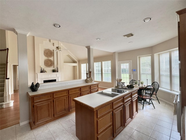 2807 Enchanted Landing Ct, Katy, TX 77494 - kitchen with black electric stovetop, a fireplace, baseboards, light countertops, and light tile patterned flooring