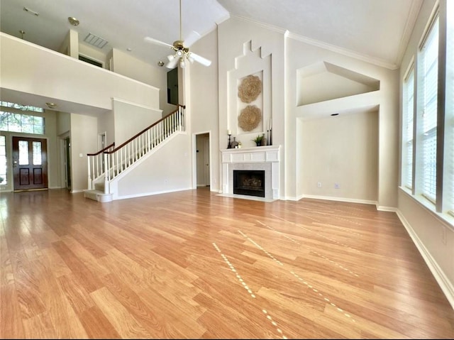 2807 Enchanted Landing Ct, Katy, TX 77494 - unfurnished living room featuring high vaulted ceiling, stairway, a fireplace with flush hearth, light wood-style flooring, and ornamental molding