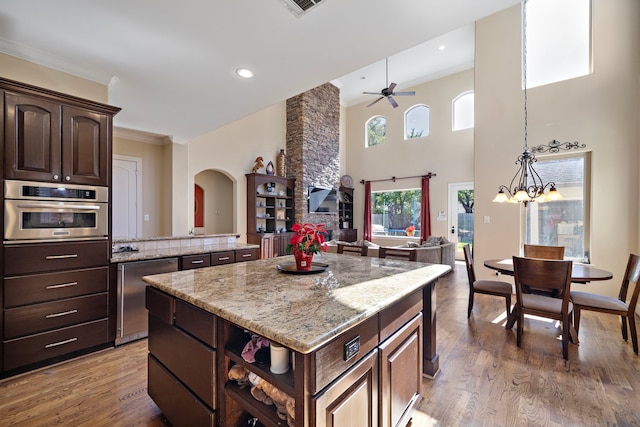 3327 Elmridge St, Houston, TX 77025 - kitchen with a center island, arched walkways, wood finished floors, ornamental molding, and light stone counters