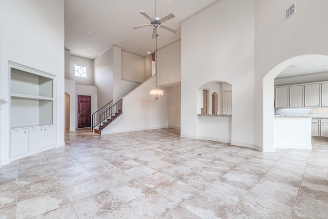 403 Harborside Way, Kemah, TX 77565 - unfurnished living room with a towering ceiling, built in features, ceiling fan, stairs, and baseboards