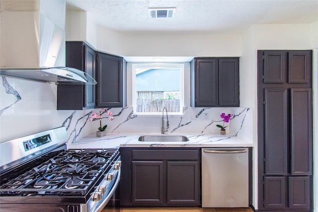 12419 Huntington Field Dr, Houston, TX 77099 - kitchen with appliances with stainless steel finishes, wall chimney range hood, a sink, light stone counters, and decorative backsplash