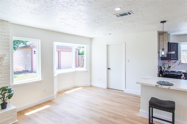 12419 Huntington Field Dr, Houston, TX 77099 - kitchen with light wood-style flooring, a textured ceiling, baseboards, stove, and a breakfast bar