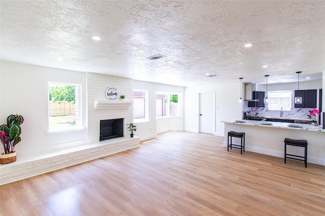 12419 Huntington Field Dr, Houston, TX 77099 - unfurnished living room with a textured ceiling, light wood-type flooring, recessed lighting, baseboards, and a fireplace