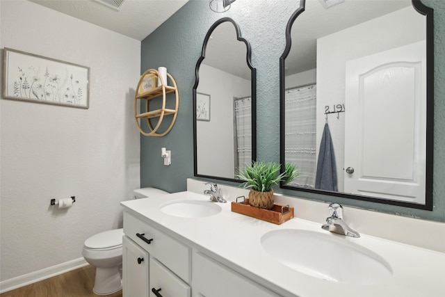 15603 Clearwater Bend Dr, Houston, TX 77044 - bathroom featuring wood finished floors, toilet, double vanity, baseboards, and a textured wall