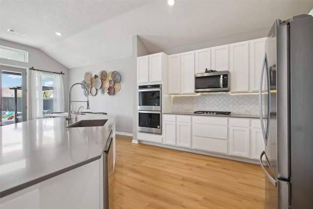 15603 Clearwater Bend Dr, Houston, TX 77044 - kitchen with stainless steel appliances, a sink, vaulted ceiling, decorative backsplash, and light wood-style flooring
