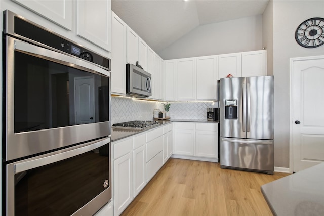 15603 Clearwater Bend Dr, Houston, TX 77044 - kitchen with stainless steel appliances, tasteful backsplash, white cabinets, lofted ceiling, and light wood-style floors