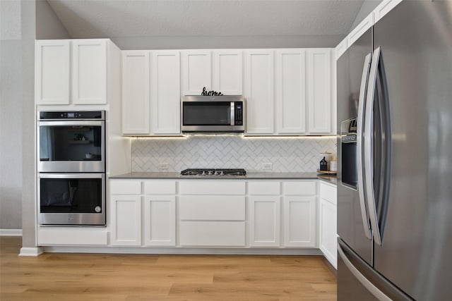 15603 Clearwater Bend Dr, Houston, TX 77044 - kitchen with stainless steel appliances, light wood-style floors, white cabinetry, and decorative backsplash