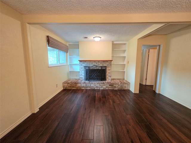11902 25th St, Santa Fe, TX 77510 - unfurnished living room featuring a textured ceiling, dark wood-style floors, a brick fireplace, baseboards, and built in shelves