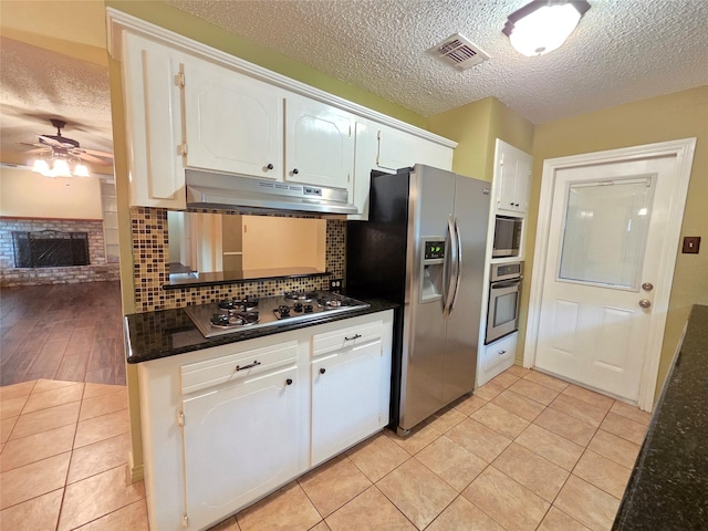 11902 25th St, Santa Fe, TX 77510 - kitchen featuring under cabinet range hood, appliances with stainless steel finishes, a ceiling fan, a textured ceiling, and white cabinetry