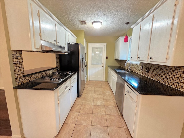 11902 25th St, Santa Fe, TX 77510 - kitchen with under cabinet range hood, stainless steel appliances, dark countertops, a sink, and a textured ceiling