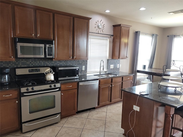 5647 Horseshoe Fls, Missouri City, TX 77459 - kitchen with appliances with stainless steel finishes, a sink, decorative backsplash, dark stone counters, and light tile patterned floors
