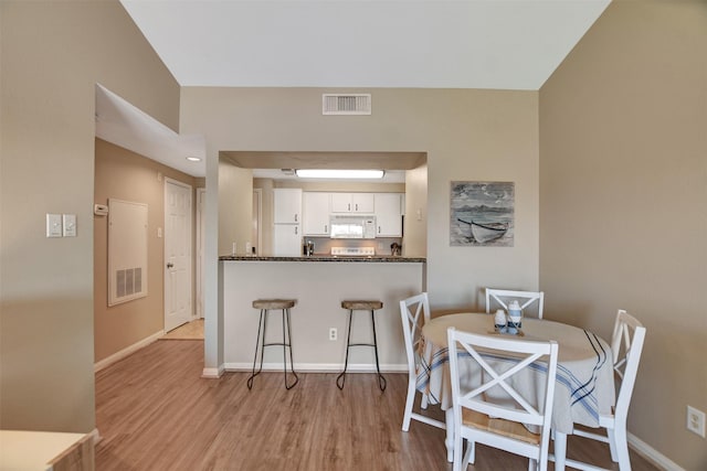 12800 Melville Dr Unit B302, Montgomery, TX 77356 - kitchen with white microwave, white cabinets, dark countertops, and light wood-style flooring
