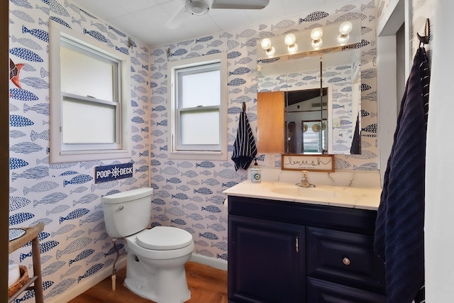 16519 Captain Kidd Rd, Jamaica Beach, TX 77554 - bathroom with wallpapered walls, toilet, a ceiling fan, vanity, and wood finished floors