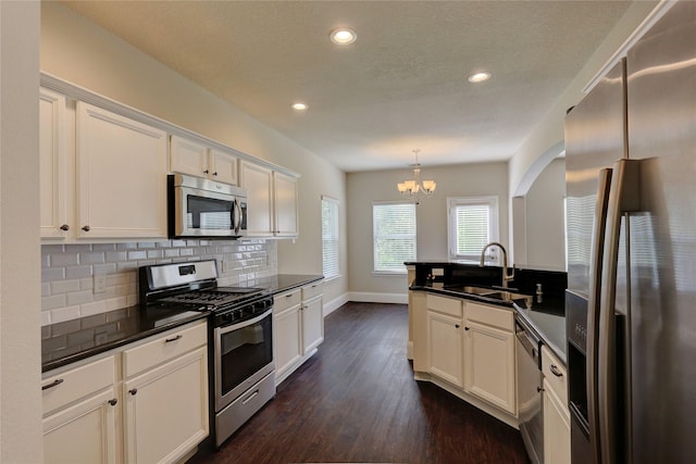 10567 Sunflower Dr, Conroe, TX 77318 - kitchen featuring appliances with stainless steel finishes, a sink, dark countertops, a chandelier, and decorative backsplash