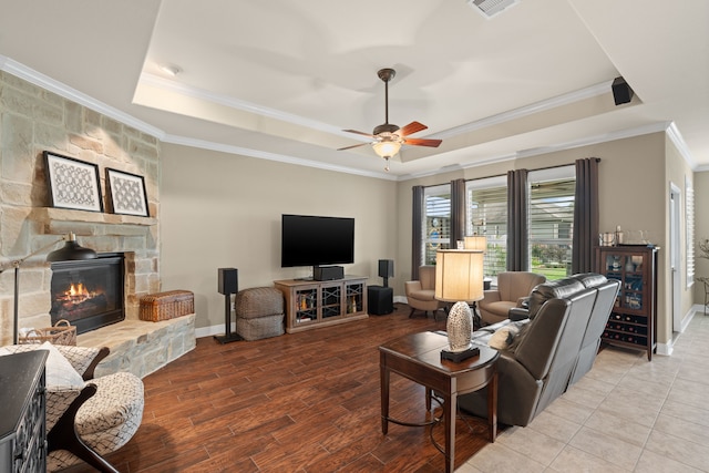 231 Ranch House Ln, Richmond, TX 77469 - living area featuring a raised ceiling, crown molding, a ceiling fan, wood finished floors, and a stone fireplace
