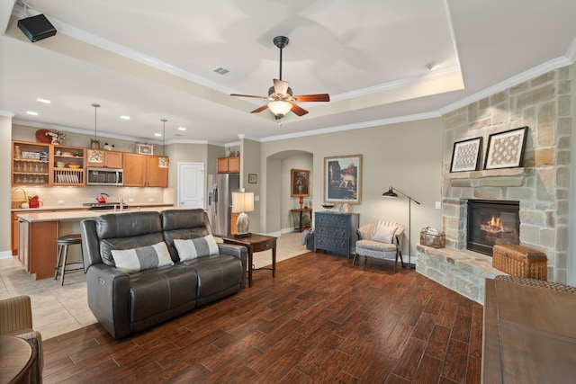 231 Ranch House Ln, Richmond, TX 77469 - living room with wood finished floors, arched walkways, a fireplace, a tray ceiling, and ornamental molding