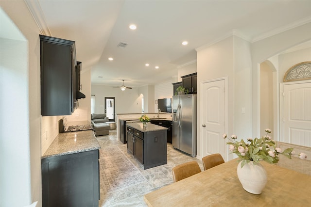 2947 Twin Cove Ct, Conroe, TX 77301 - kitchen featuring stainless steel fridge with ice dispenser, a kitchen island, crown molding, ceiling fan, and arched walkways