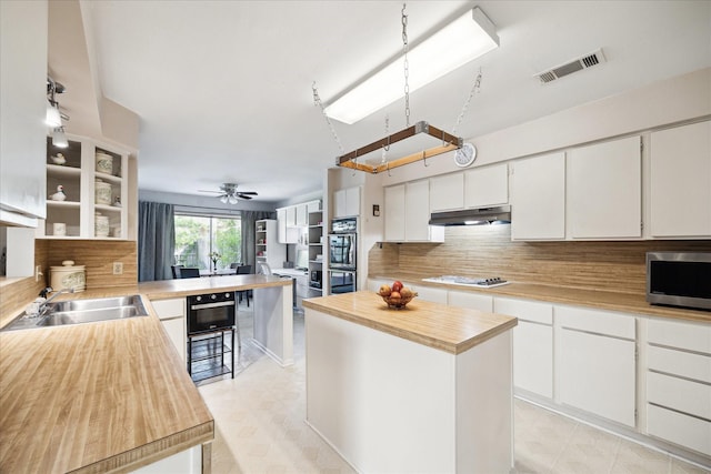 1939 Ash Meadow Dr, Houston, TX 77090 - kitchen featuring wooden counters, stainless steel microwave, a sink, under cabinet range hood, and double oven