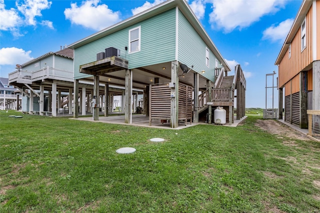 1317 Emerald Dr, Crystal Beach, TX 77650 - rear view of property featuring stairway, a lawn, and central AC