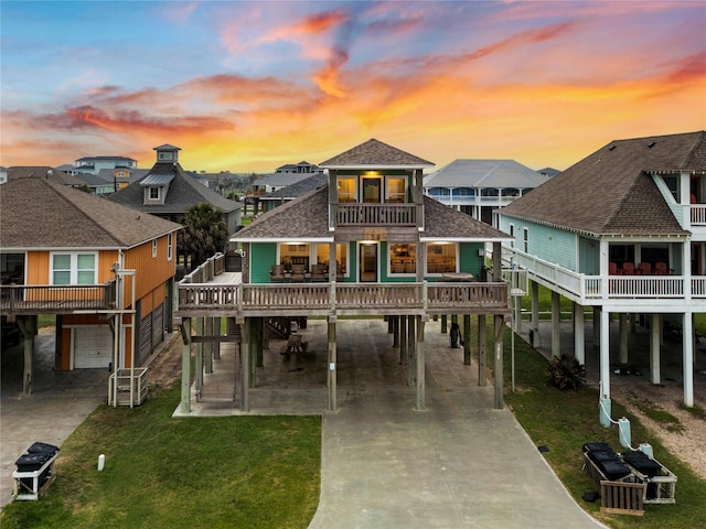 1317 Emerald Dr, Crystal Beach, TX 77650 - back of house at dusk with a carport, concrete driveway, roof with shingles, and a balcony
