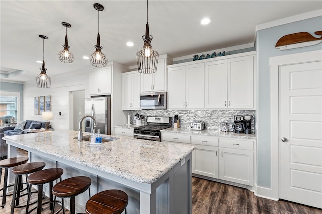 1317 Emerald Dr, Crystal Beach, TX 77650 - kitchen featuring appliances with stainless steel finishes, a sink, backsplash, a breakfast bar, and white cabinets